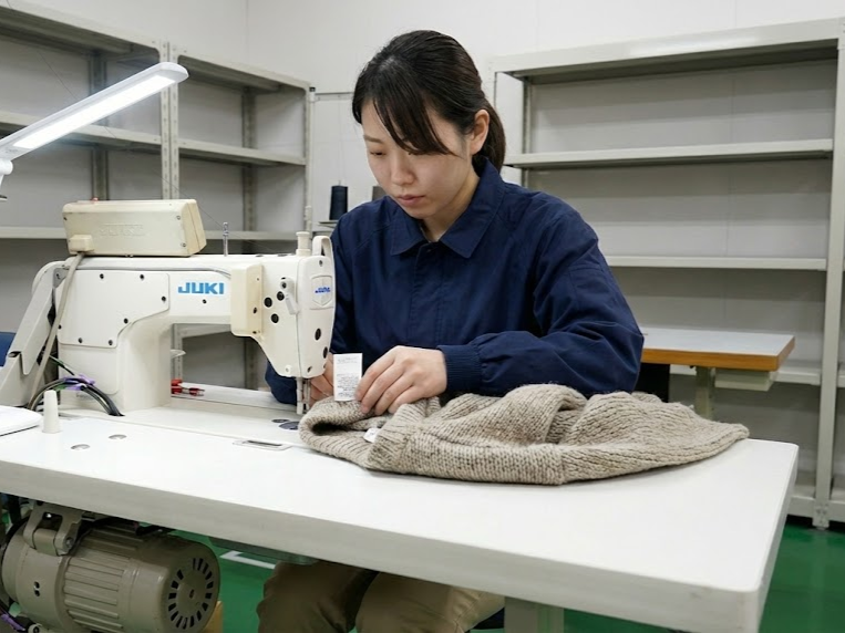 日本の法律に準拠して社内で作成・発行された洗濯絵表示やインカードを商品に縫い付けている様子